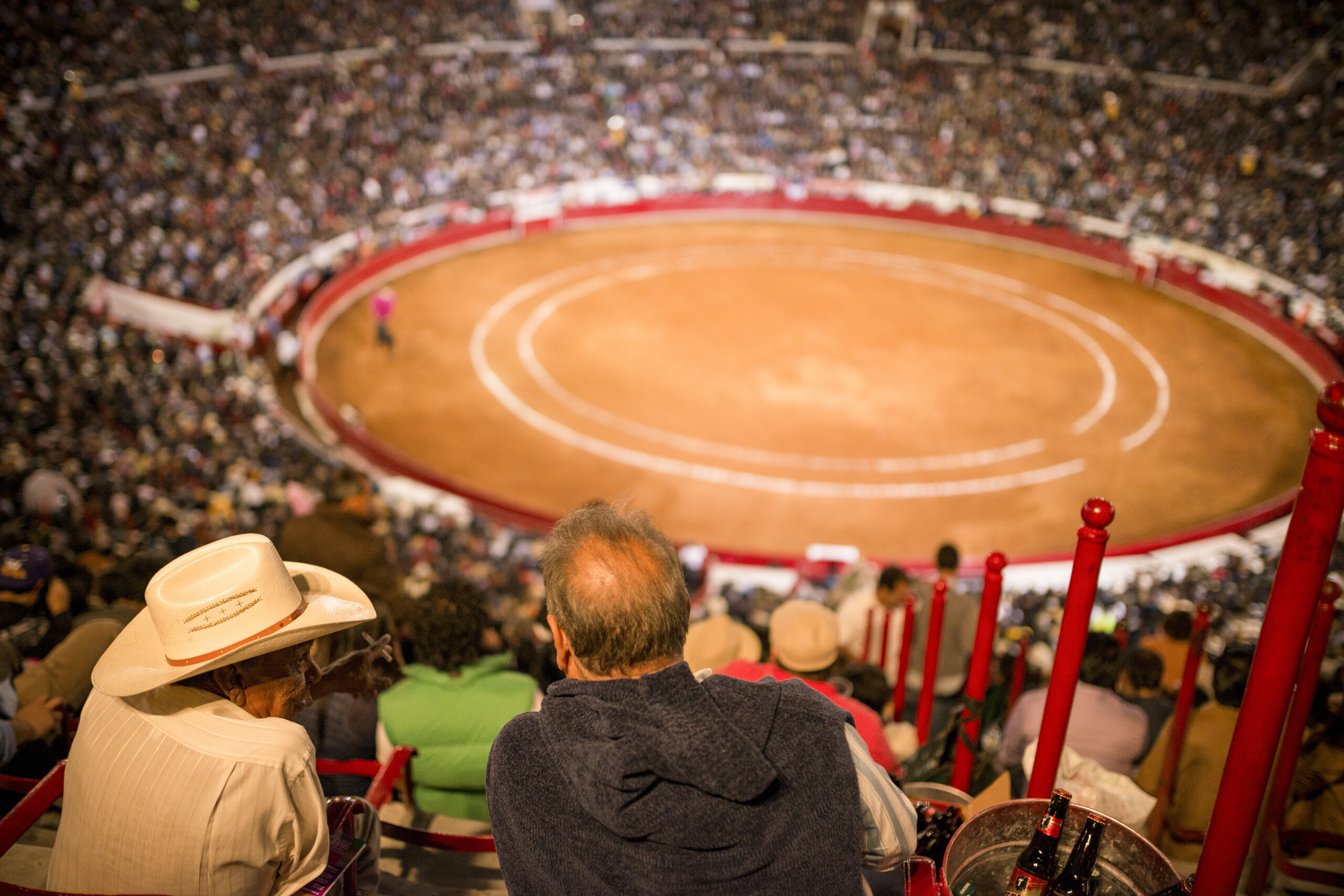 Spectators gazing at a bullfighting arena from the stands.
